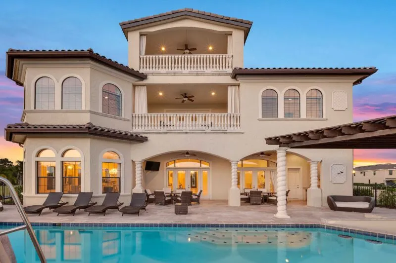 Three-storey Orlando luxury villa with arched balconies and pool glowing at sunset 