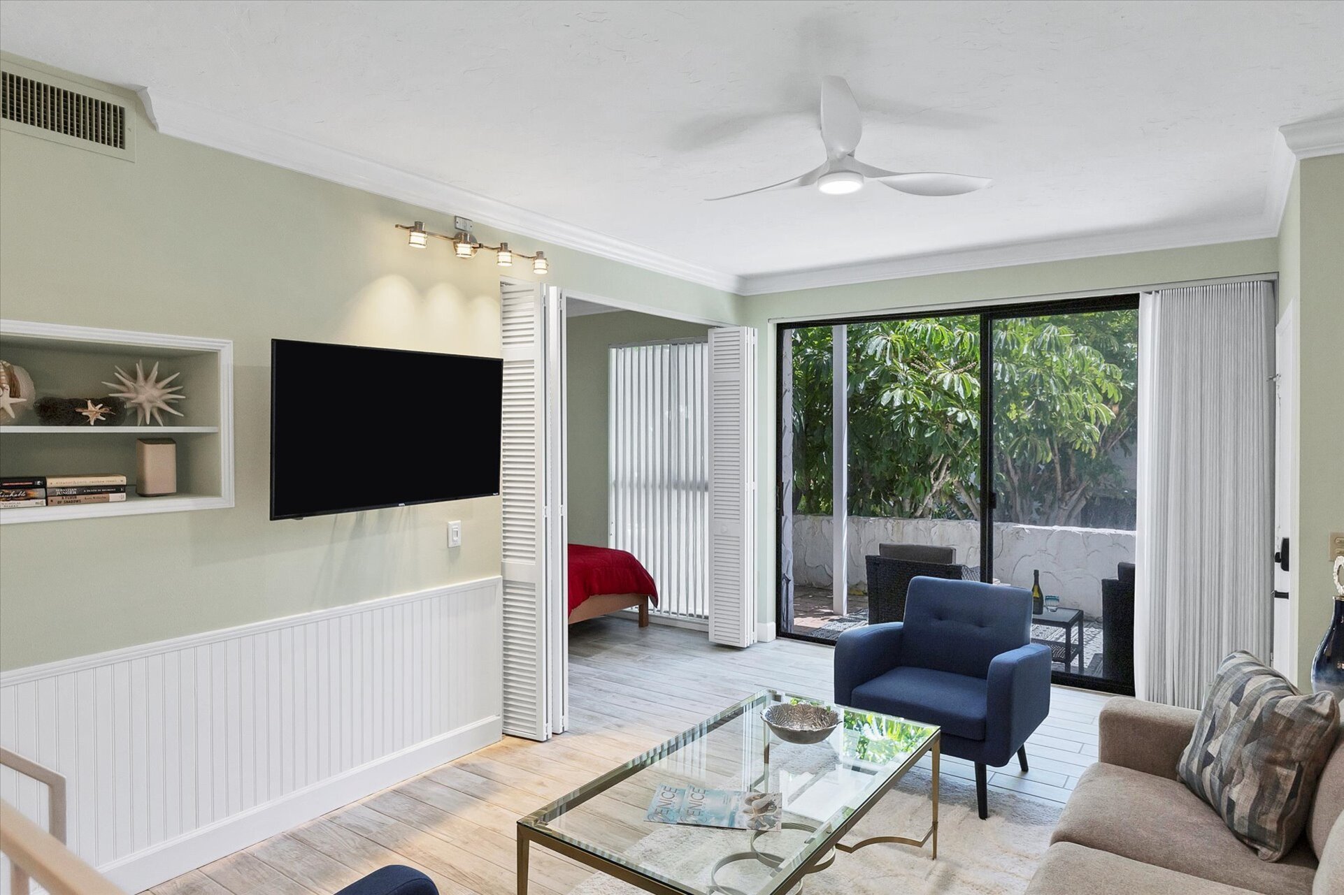 Living room with 55-inch TV, balcony access, and queen sofa bed