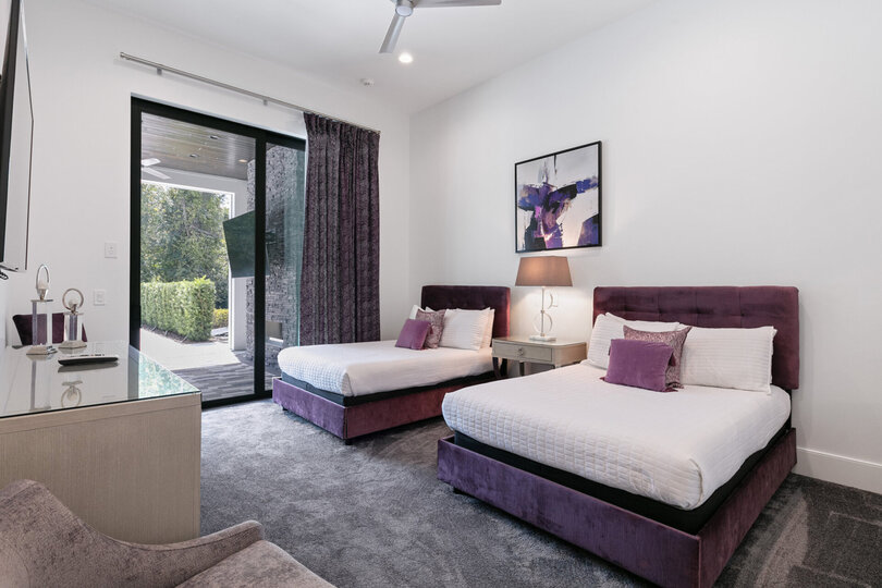 First-floor bedroom furnished with two full-size beds with access to the covered patio